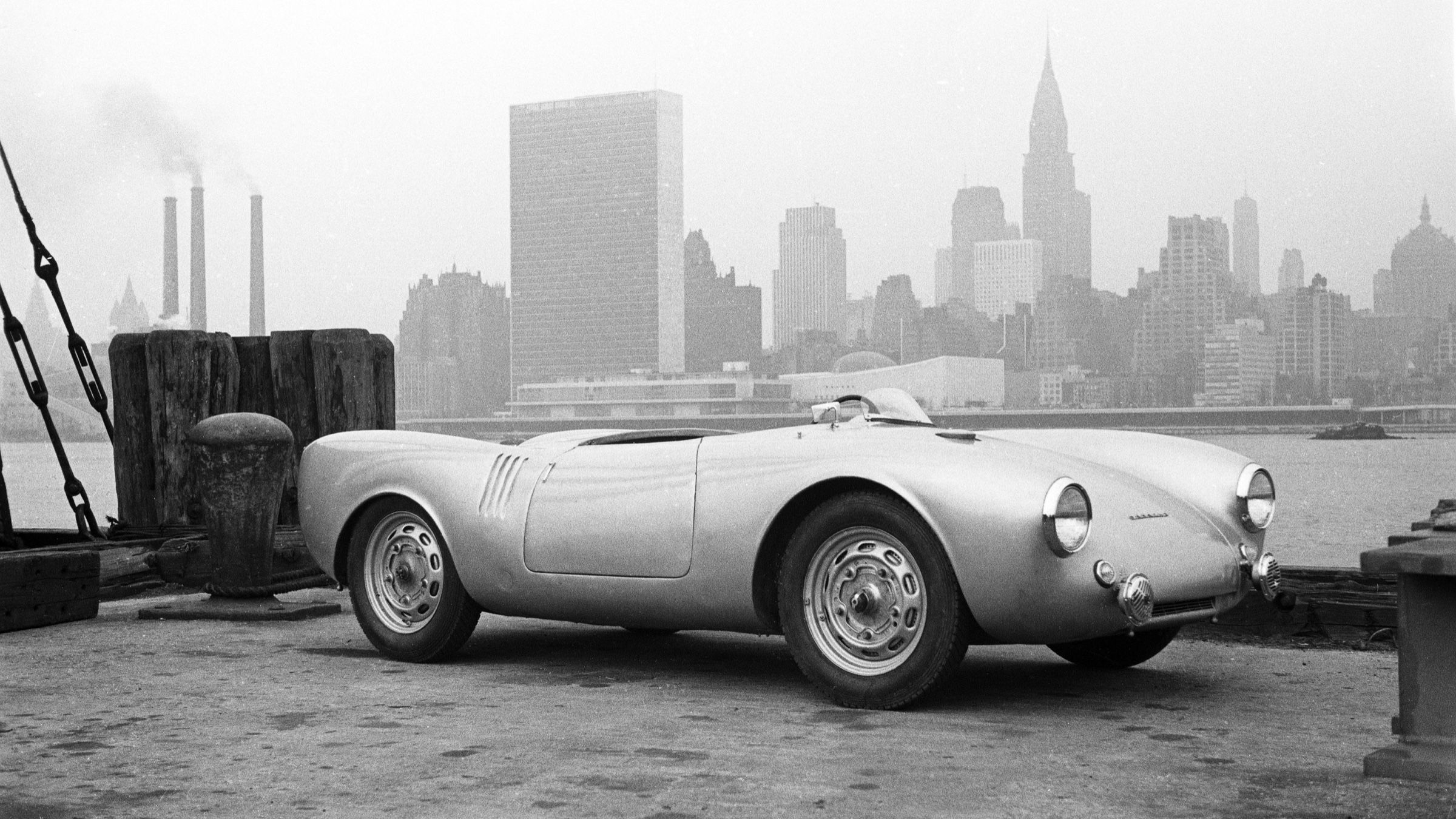Black and white 1953 photograph of a Porsche 550 Spyder on the same Queens pier