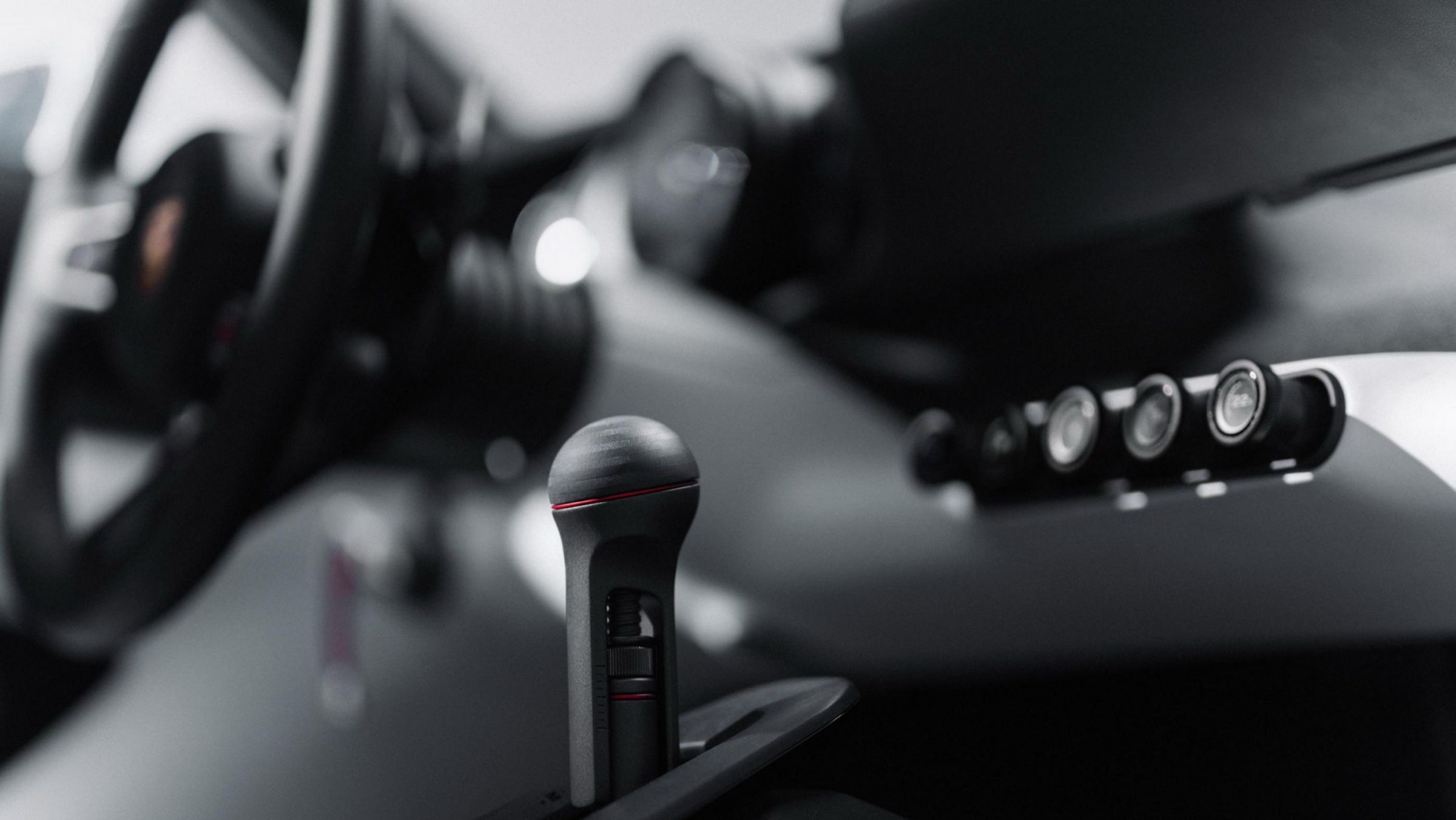 Close-up of the gear lever and a row of round controls in soft focus