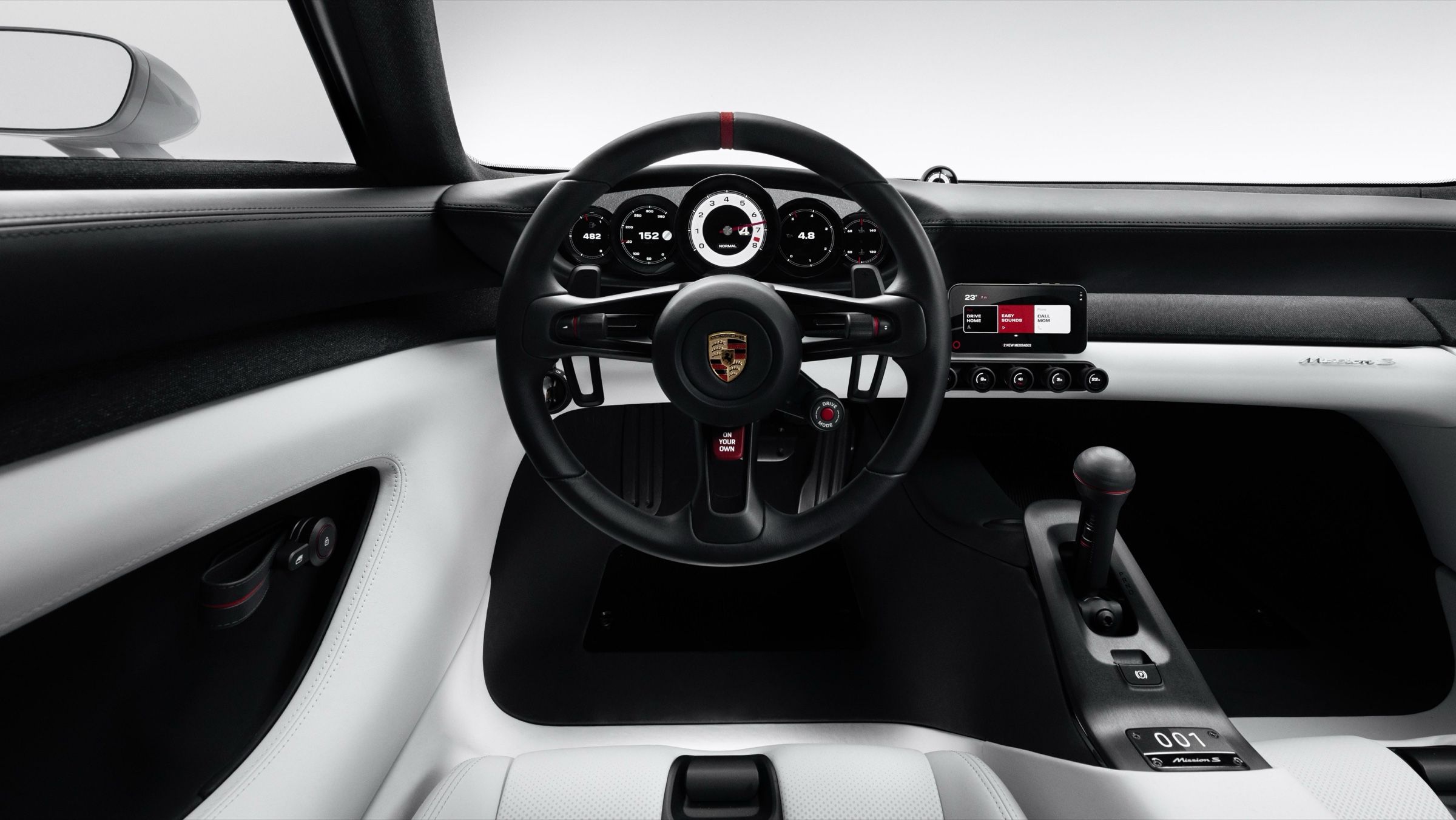 Driver view of the dashboard: a round steering wheel, five round instruments, a phone in a holder on the right and a tall gear lever